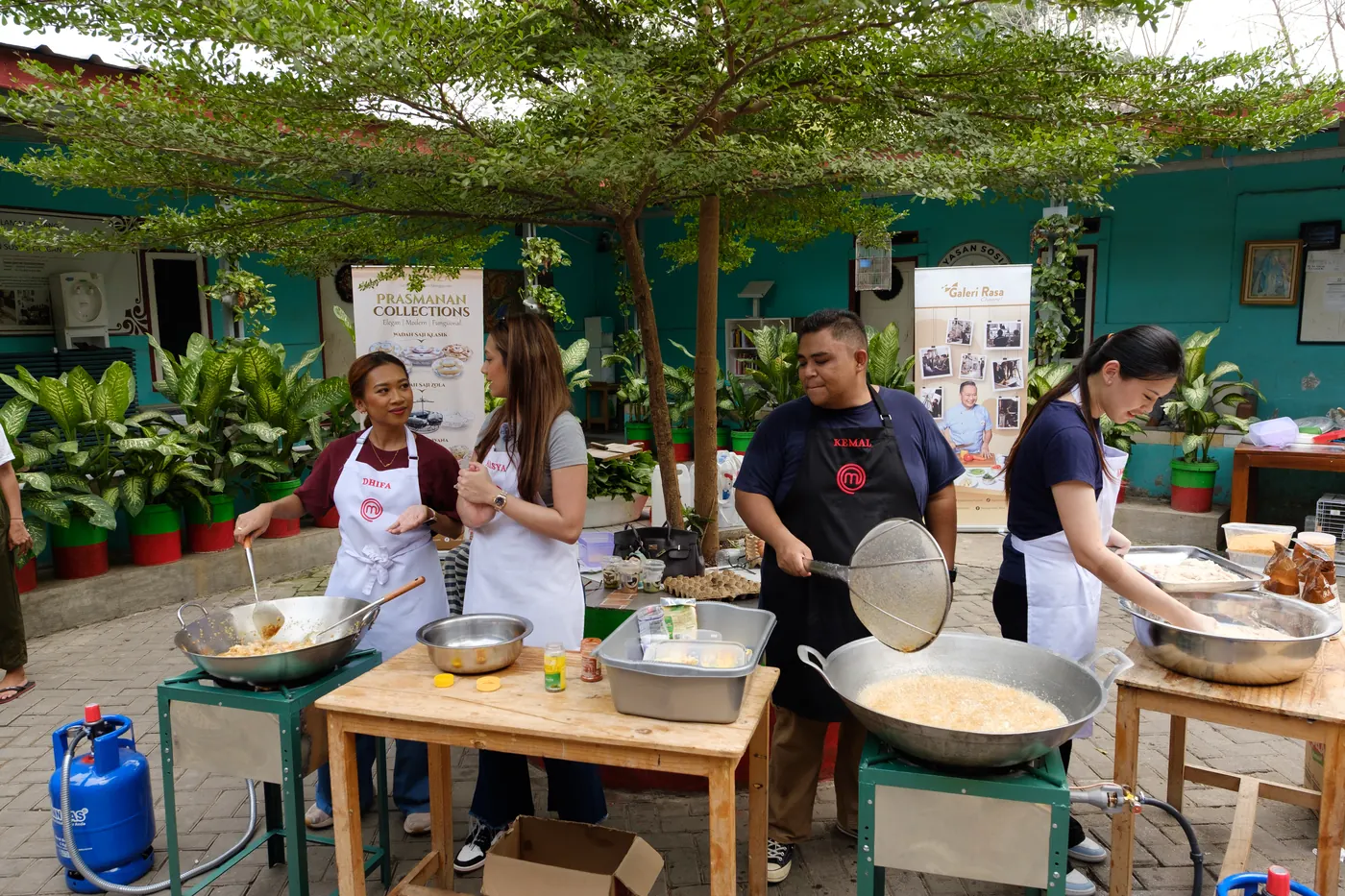 Para chef memasak di bawah pohon halaman yayasan