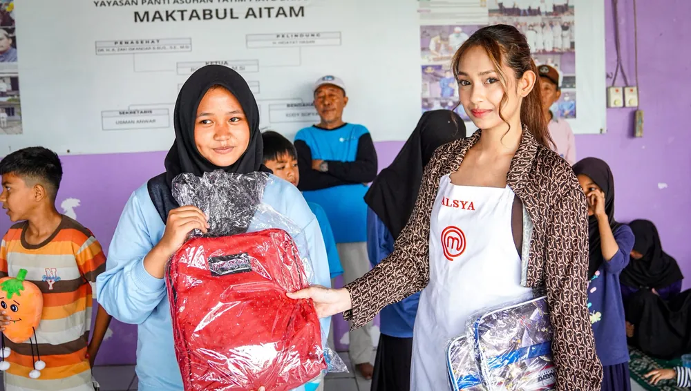Chef Alsya Arona menyerahkan tas sekolah kepada seorang anak